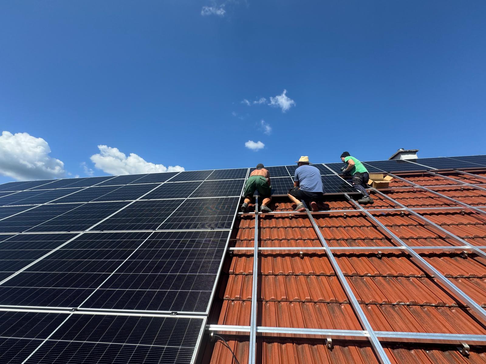 Monteure beim Verlegen von PV-Modulen auf einem großen Ziegeldach